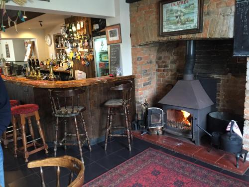 a bar with a fireplace and a bar with stools at Red Lion Inn in Sidbury
