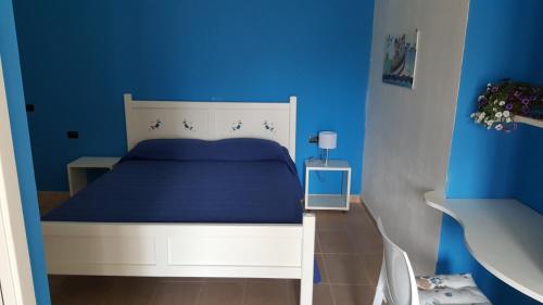 een blauwe slaapkamer met een wit bed en een blauwe muur bij Casa con ampio giardino Sulcis in Giba