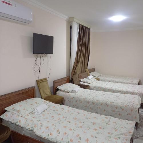 Un dormitorio con tres camas y un televisor en la pared. en Guest House Javlonbek, en Samarkand