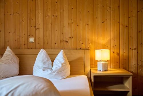 a bedroom with a bed with white pillows and a lamp at Haus Versettla in Gaschurn