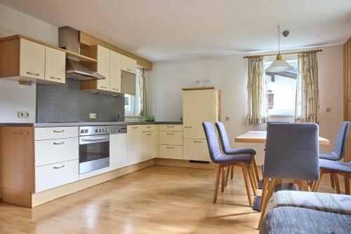 a kitchen with white cabinets and a table and chairs at Haus Versettla in Gaschurn