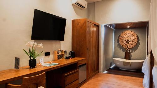 a room with a bathroom with a tub and a tv at Lovina Haven Boutique Resort in Lovina
