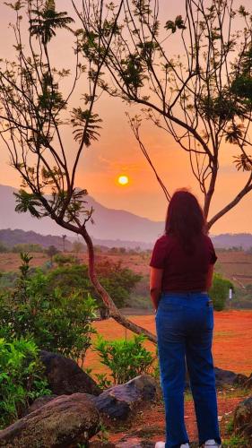 a woman standing in front of a sunset at Serenity View in Batheri
