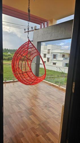 a red hammock hanging in a room with a wooden floor at Shree Gowthameshwara Nilaya in Chikmagalūr