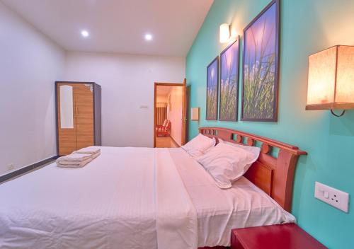 a bedroom with a large white bed with blue walls at Pine Forest View Ooty by VOYE HOMES in Ooty