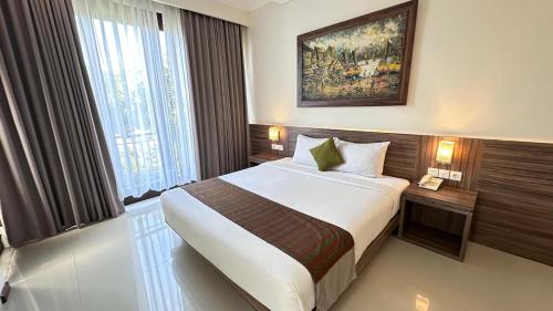 a hotel room with a large bed and a window at Argya Santi Resort in Jimbaran