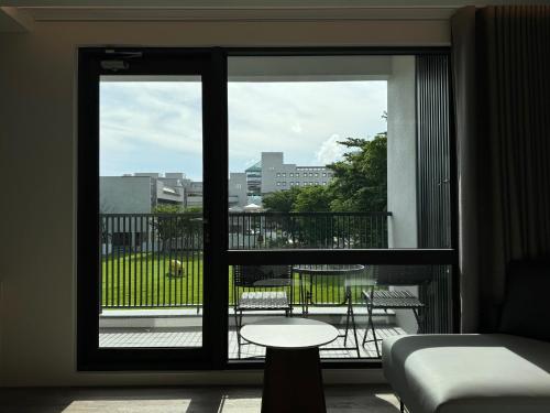 a room with a window with a table and a balcony at Lihe Jiazhu in Tainan