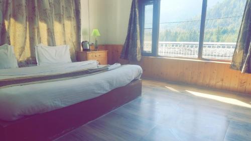 a bedroom with a bed and a large window at Singh Saab Rooms & Cafe in Manāli