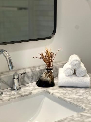 a bathroom sink with towels and a vase with flowers at Cozy 2BR Apt with Parking, Steps to Brown and RISD in Providence