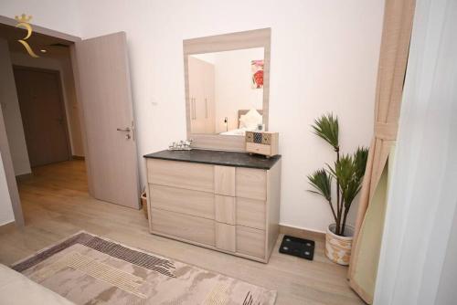 a bathroom with a vanity with a mirror and a plant at 1BR Stylish Apartment - Rossa Urban Yas Island in Abu Dhabi