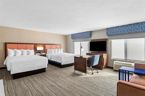a hotel room with two beds and a television at Hampton Inn & Suites Farmington in Farmington