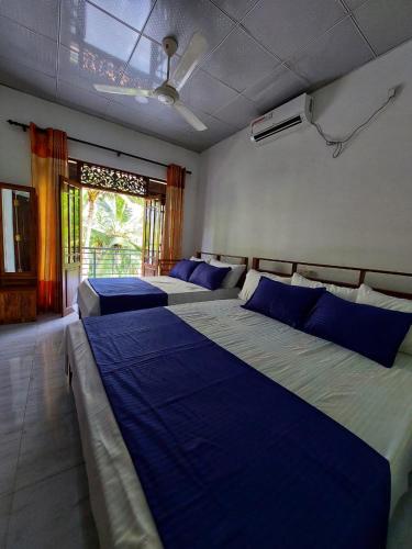 a bedroom with two beds with blue sheets and a window at Wijaya Home Stay in Anuradhapura