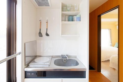 een kleine keuken met een spoelbak en een spiegel bij 3-minute walk from Shin-Okubo Station -Shobi Buildding- in Tokyo