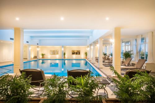 une piscine dans un hôtel avec des chaises et des plantes dans l'établissement Hotel Palace Bellevue - Liburnia, à Opatija