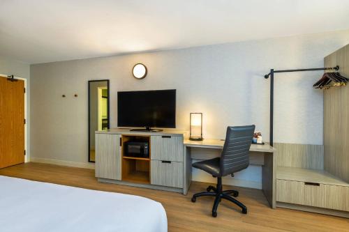 a bedroom with a desk with a television and a chair at Comfort Inn Airport East in Quebec City