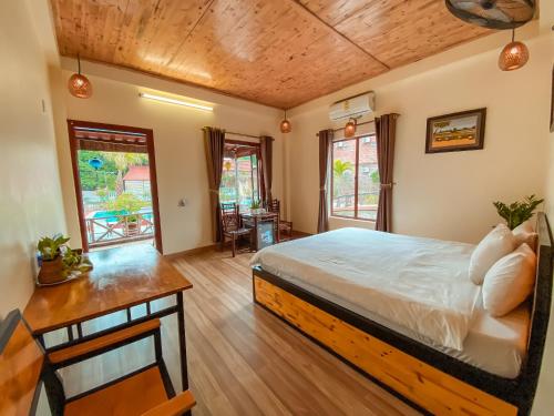 a bedroom with a bed and a desk and windows at Trang An Village Homestay in Ninh Binh