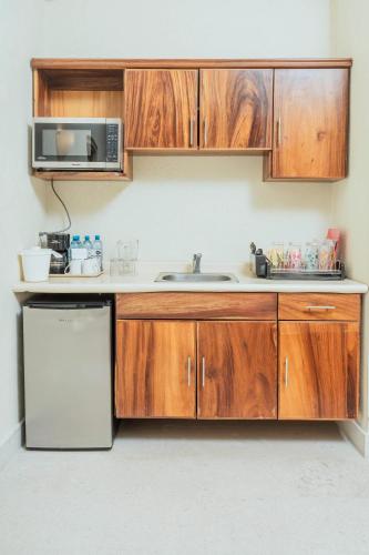 a kitchen with wooden cabinets and a sink and a microwave at Comfort Inn Puerto Vallarta Golfside & Marina in Puerto Vallarta