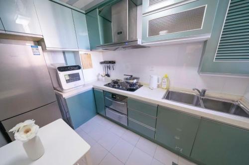 a small kitchen with green cabinets and a sink at Book and Bed-People's Square in Shanghai