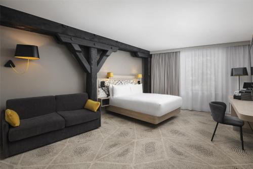 a hotel room with a bed and a couch at Hilton Garden Inn Paris La Villette in Paris