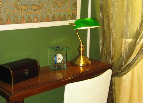 a desk with a green lamp and a clock on it at B&B Via Roma in Cesate