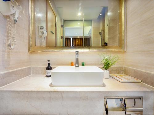 a bathroom with a white sink and a mirror at Vienna Hotel Guangzhou Baiyun International Airport Branch in Guangzhou