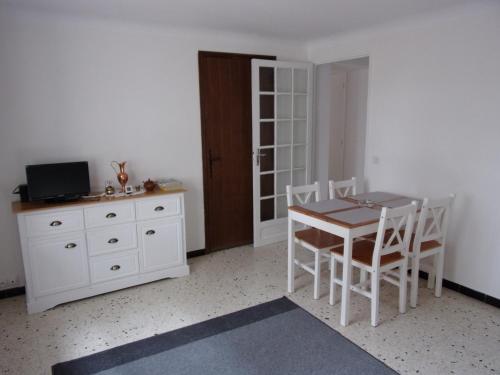 ein Esszimmer mit einem Tisch und weißen Stühlen in der Unterkunft Appartement L'oranger in Pégomas