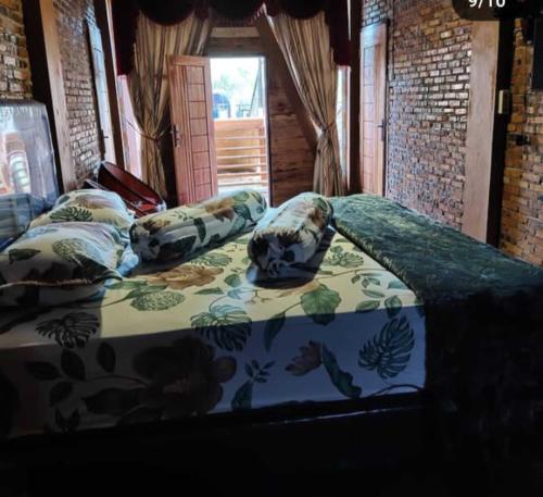 a bed with pillows on it in a room at Villa Della Puncak 2000 Siosar in Talunkota