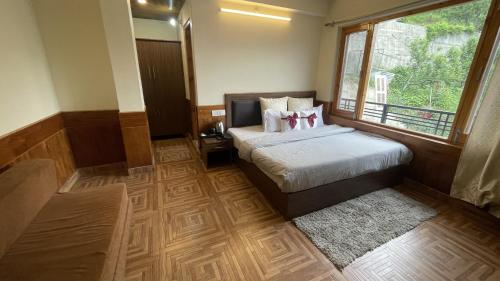 a bedroom with a bed and a large window at Singh Saab Rooms & Cafe in Manāli