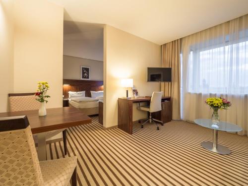 ein Hotelzimmer mit einem Schreibtisch und einem Bett in der Unterkunft Hotel an der Oper in Chemnitz