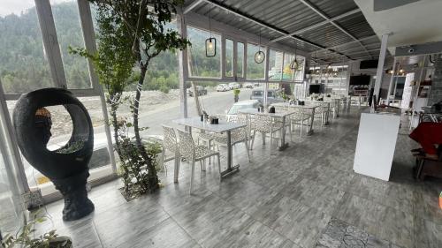a restaurant with tables and chairs in a room with windows at Singh Saab Rooms & Cafe in Manāli