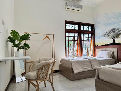 Un dormitorio con dos camas y una silla y una ventana. en Ijen Vibe's Inn, en Banyuwangi