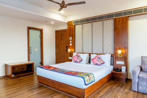 a bedroom with a bed and a chair at Hotel Paandora Grand,Udaipur in Udaipur