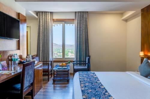 a hotel room with a bed and a dining table at Hotel Paandora Grand,Udaipur in Udaipur