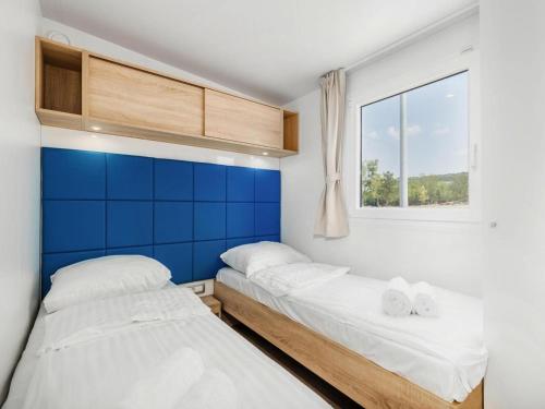 two beds in a small room with a window at Mobile Home in Omisalj by Pusca Bay Beach in Omišalj