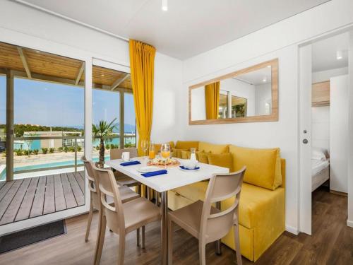 a dining room with a yellow couch and a table and chairs at Mobile Home in Omisalj by Pusca Bay Beach in Omišalj