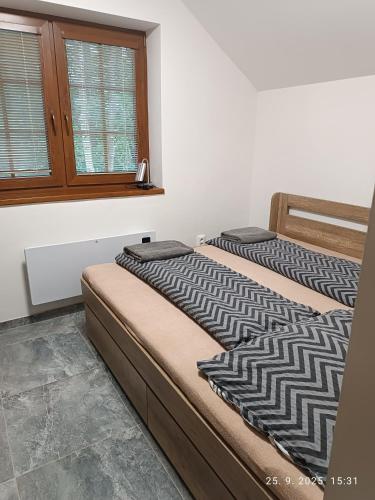 two beds in a room with a window at Chata dobrý pocit in Horné Orešany