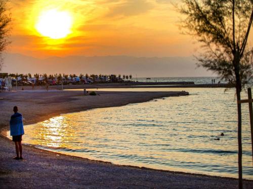 a person standing on the beach watching the sunset at Mobile Home in Omisalj by Pusca Bay Beach in Omišalj