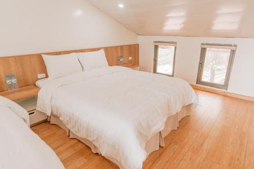 a bedroom with a large white bed and two windows at Sunny Camping Sóc Sơn in Sóc Sơn