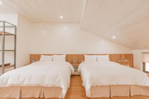 two beds in a room with white sheets at Sunny Camping Sóc Sơn in Sóc Sơn