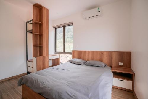 a bedroom with a large bed with a wooden headboard at Sunny Camping Sóc Sơn in Sóc Sơn