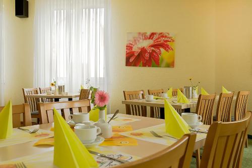 a dining room with tables and chairs with yellow napkins at Apart Hotel Gera in Gera