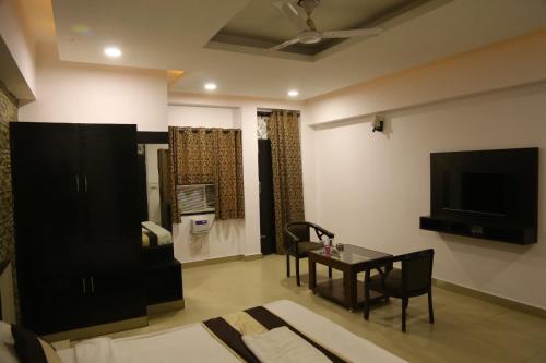 a living room with a table and a tv at Rockwood Inn in Faridabad