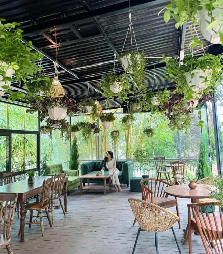 a woman sitting on a couch in a patio with tables and chairs at Sunny Camping Sóc Sơn in Sóc Sơn
