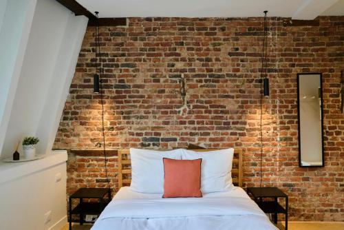eine Ziegelwand hinter einem Bett mit einem roten Kissen in der Unterkunft Old Town - Nice studio in Lille