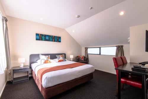 a bedroom with a large bed with a desk and a desk at 298 Westside Motor Lodge in Christchurch