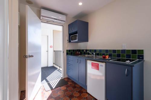 a kitchen with blue cabinets and a sink at 298 Westside Motor Lodge in Christchurch