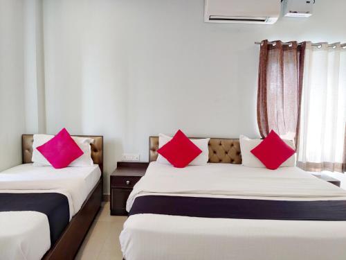 two beds in a room with pink pillows on them at Hotel Yamunotri Retreat, Rishikesh in Rishīkesh