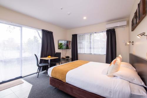 a bedroom with a bed and a desk and a window at 298 Westside Motor Lodge in Christchurch