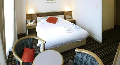 a hotel room with a bed and two chairs at Pearl Hotel Mizonokuchi in Yokohama
