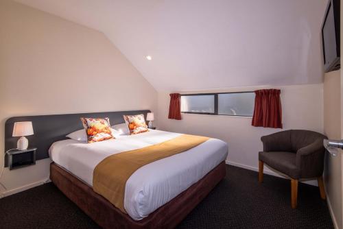 a bedroom with a large bed and a chair at 298 Westside Motor Lodge in Christchurch